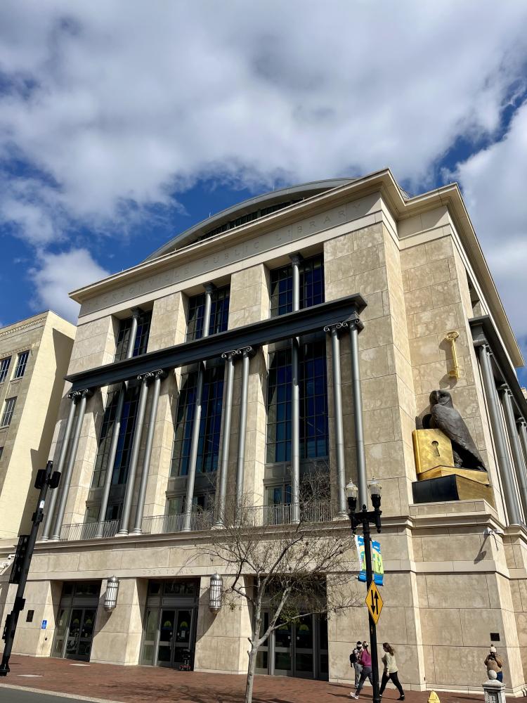 Large stone building with tall columns under a partly cloudy sky.